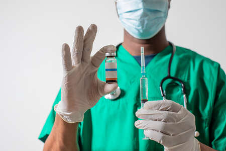 Doctor in medical mask holding syringe with medicationの写真素材