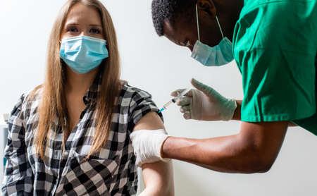 Doctor in medical mask holding syringe with medication