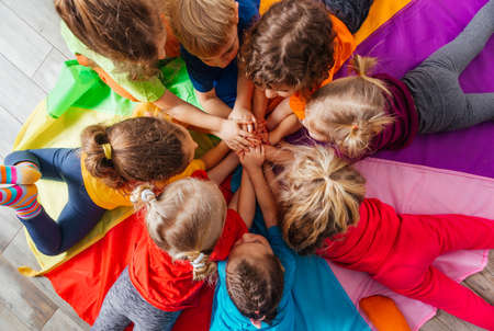 Cheerful children playing team building games on a floorの写真素材