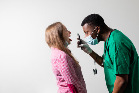 Doctor uses smartphone light to check patients throatの写真素材
