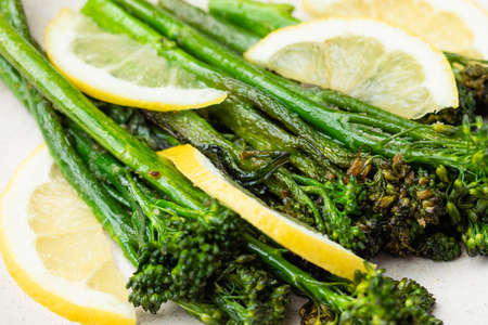 Cooked fresh broccolini with lemon on the plateの写真素材