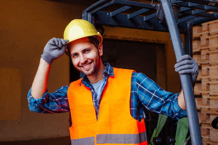 The young worker stands near a forklift in a factoryの写真素材