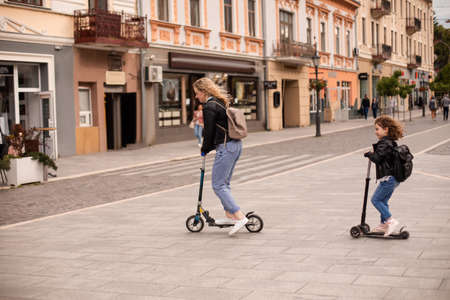 The stylish young mom and daughter are riding scootersの写真素材