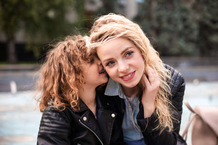 Mom and daughter are whispering while walking around the cityの写真素材
