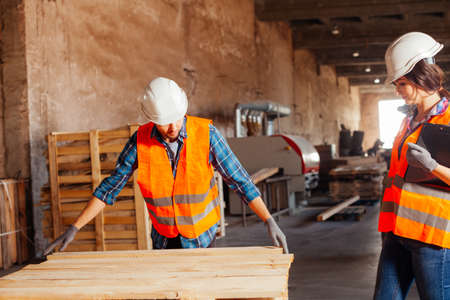 The woman inspector checks the work of a man in a warehouse