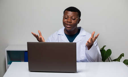 Cheerful doctor sitting in front of laptop during videocallの写真素材