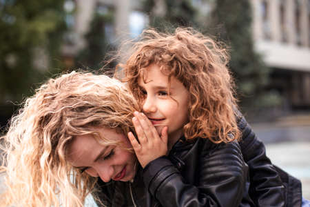Mom and daughter are whispering while walking around the city