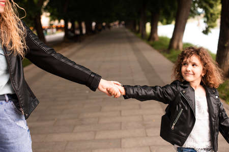 The mom and little girl walk around the city are holding handsの写真素材
