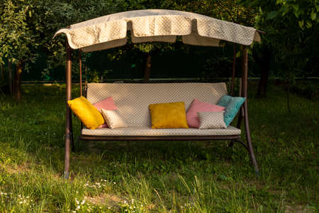 The comfortable swing with pillows in the backyard in summerの写真素材