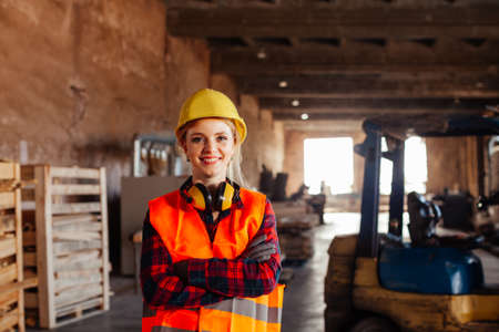 The woman woodworker chooses a board in a warehouse