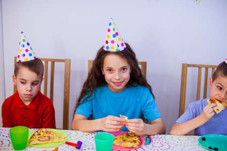 the little kids are eating pizza at the birthday partyの写真素材