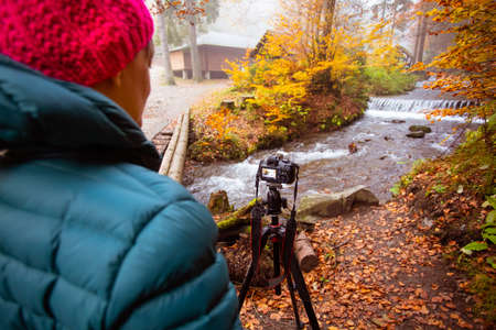 Woman photographer takes a photo forest waterfall in the autumnの写真素材