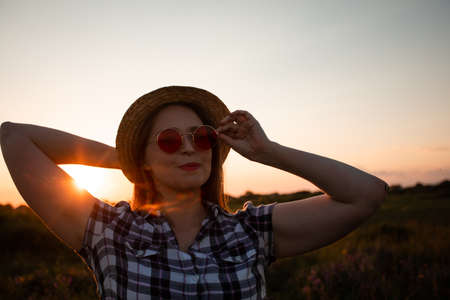 Girl in hat enjoying warm summer eveningの写真素材