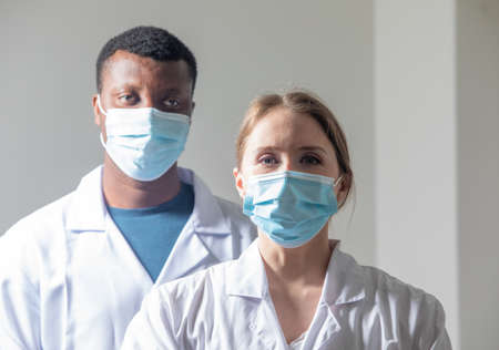 Diverse male and female doctors in white medical masksの写真素材