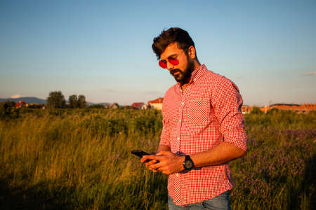 Outdoor picture handsome men with smartphone on summer farmlandの写真素材