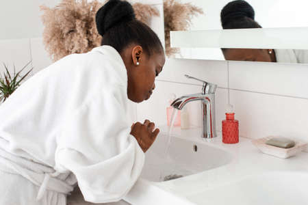 Woman refreshing face, washing it in basin