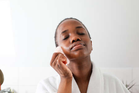 Lovely african girl massaging face with rose quartz gua sha