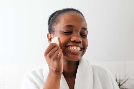 Lovely african girl massaging face with rose quartz gua shaの写真素材