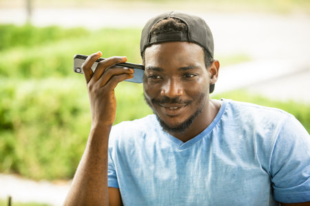 Smiling african american man listening audio messageの写真素材