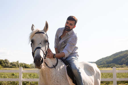 The handsome man rides a horse on a ranchの写真素材