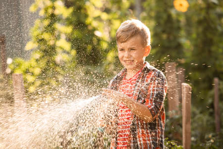 The little boy waters the plants making large splashes of waterの素材 [FY310174273132]