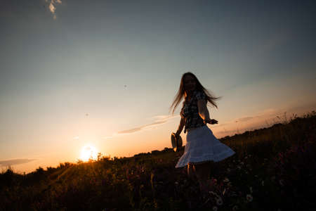 Girl enjoying freedom watching sunset in meadowの写真素材
