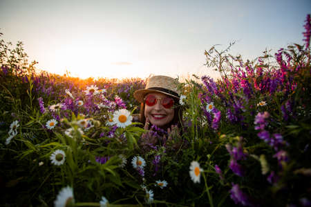 Artistic portrait of woman in red glasses among flowersの写真素材