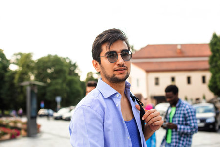 The handsome student is hugging a stack of books outdoorsの写真素材