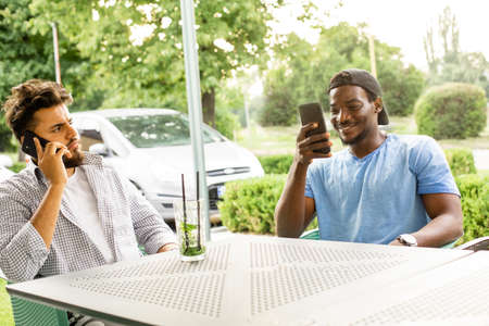 Diverse young friends talking via video call outdoors