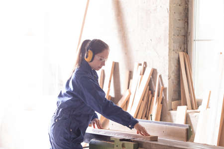 Gender equality concept. Young female carpenter at woodworking factoryの写真素材