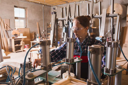 Experienced female craftman work with woodworking machinery. Furniture production