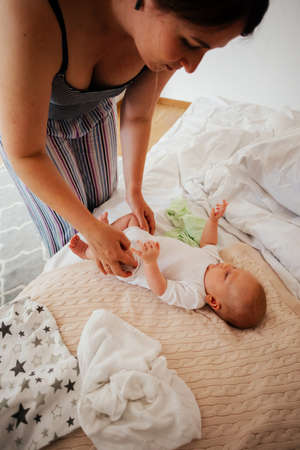 Mother change reusable diaper on her baby on the bedの写真素材
