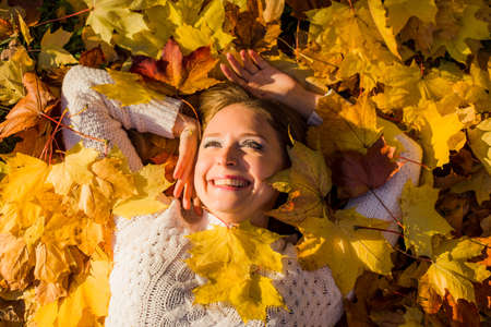 Woman laying in maple leaves in the park.