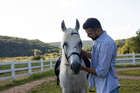 The handsome man is looking into the eyes of a horseの写真素材