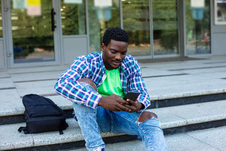 The pensive student sits in front of the university buildingの写真素材