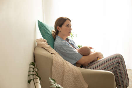 Comfortable and tranquil breastfeeding in cosy armchair at homeの写真素材