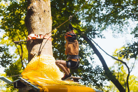 The concentrated girl carefully overcomes obstacles in the rope parkの写真素材