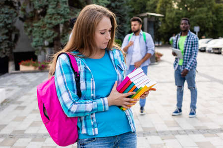 The female student is holding a stack of books outdoorsの写真素材