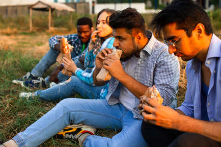 The group of young diverse people eating fastfood on natureの写真素材