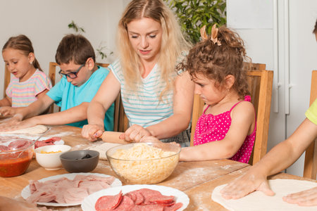 the teacher is learning children to cook pizzaの写真素材