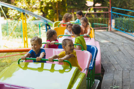 The happy kids on a roller coaster in the amusement parkの写真素材