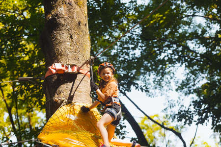 The concentrated girl carefully overcomes obstacles in the rope parkの写真素材