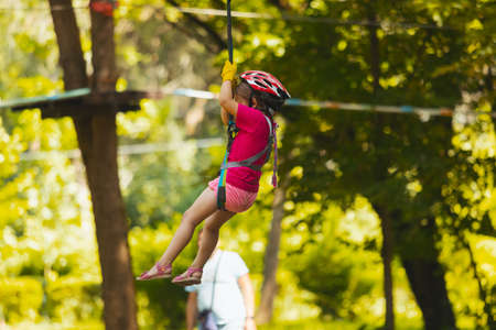 The little girl goes down the zipline in the parkの写真素材