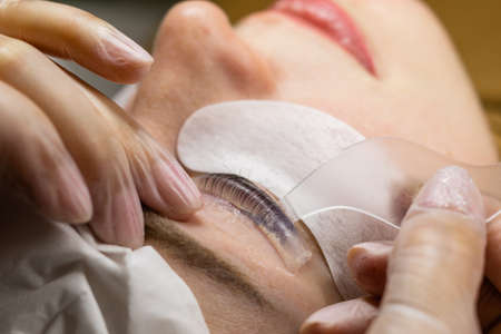 Female face under procedure of eyelashes lamination in beauty salon