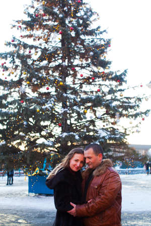 The beautiful couple stands at the background of the Christmas tree in the cityの写真素材
