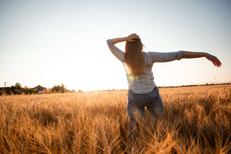 Peaceful woman wellcoming the rising sun in fieldの写真素材