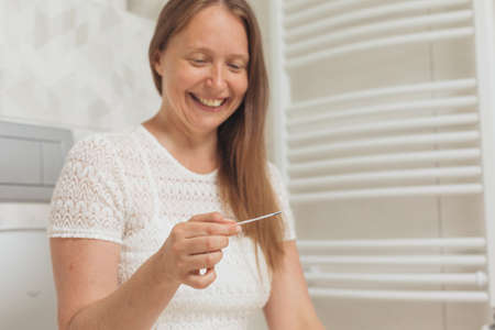 Middle age woman with pregnancy test in restroomの写真素材