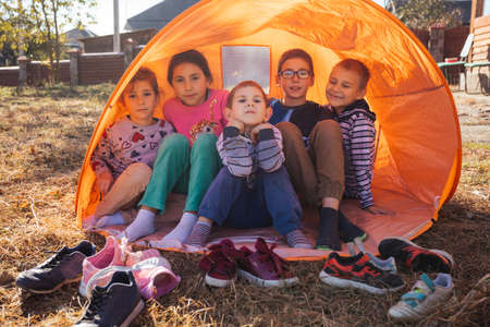 Happy kids - boys and girls in a tent outdoorの写真素材