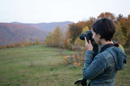 Woman trekking in the forest and taking pictures with dlsr cameraの写真素材