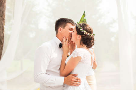 Kissing couple under the flower arch at the wedding ceremonyの写真素材